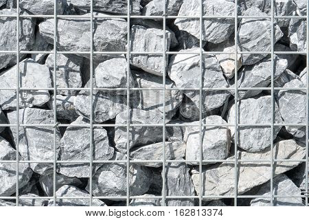 Steel mesh of gabion wall.Grey stones in gabion.