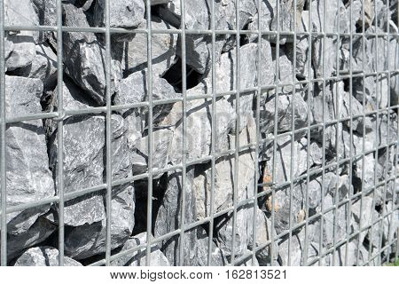 Steel mesh of gabion wall.Grey stones in gabion.