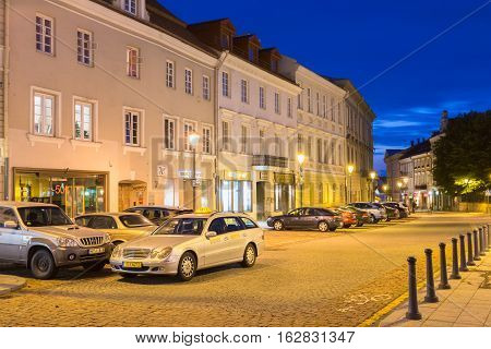 Vilnius, Lithuania - July 8, 2016: The Motionless Silver Mercedes Benz Taxi Car Among Parked Automobiles On Deserted Rotuses Square In Evening Illumination Under Summer Blue Sky.
