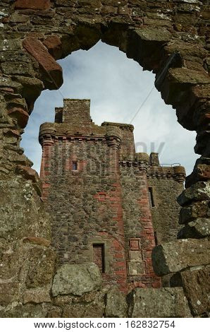 A view of Balvaird castle through a hole in a wall