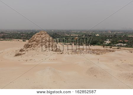 Step pyramid in the desert in Egypt near green mango plantation