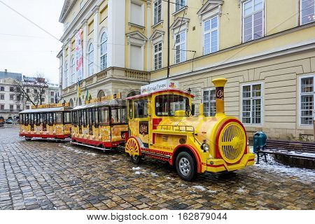 Ukraine Lviv - December 15 2016: Sightseeing road train in the Rynok Square next to Lviv city council expects tourists for a sightseeing tour of the city of Lviv.