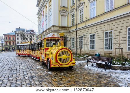 Ukraine Lviv - December 15 2016: Sightseeing road train in the Rynok Square next to Lviv city council expects tourists for a sightseeing tour of the city of Lviv.