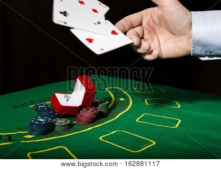 casino chips and a precious ring on a green poker table background, man throws cards with losing combination