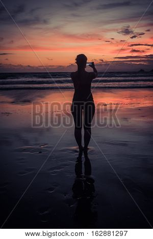 Sunset warm and cold. Girl backlit taking photo