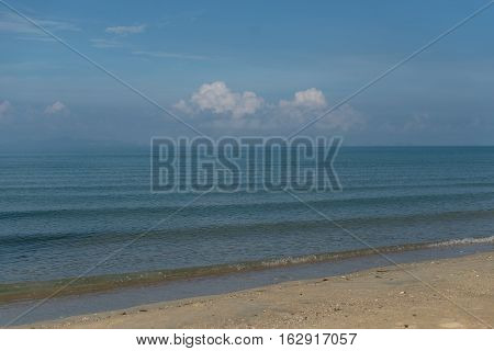shore of the calm morning sea against the blue sky and white clouds