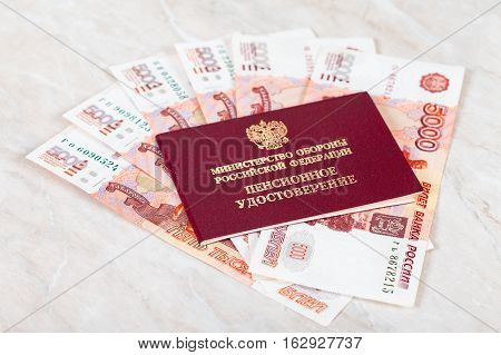 MOSCOW RUSSIA - DECEMBER 18 2016: Russian Pension Certificate and money. Inscription on Certificate in russian: "Russian Ministry of Defense" "Pension Certificate"