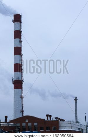 high pipe CHP on the background of blue sky fog smog and out clouds of thick smoke pipe red-and-white it's cold outside