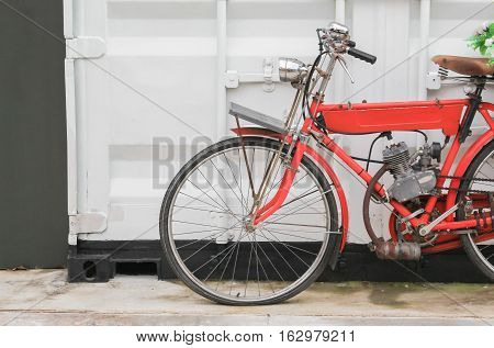vintage bicycle red which has motor near of wall white background