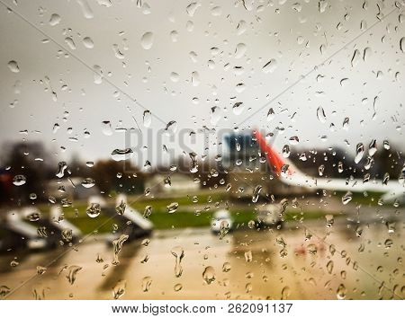 Water Drop On Mirror Window Of Airplane In Rainy Day While Landing At Airport With Blur Aircraft Out