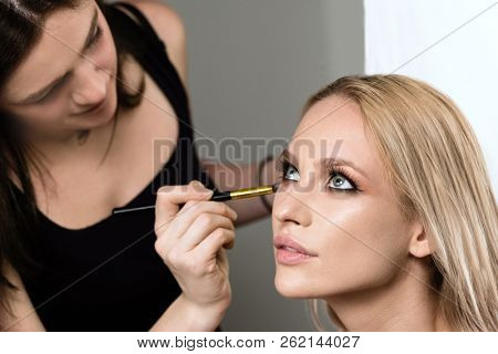 makeup styl?st apply?ng makeup on the model closeup beauty face