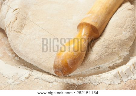 yeasty dough and rolling pin on wooden surface