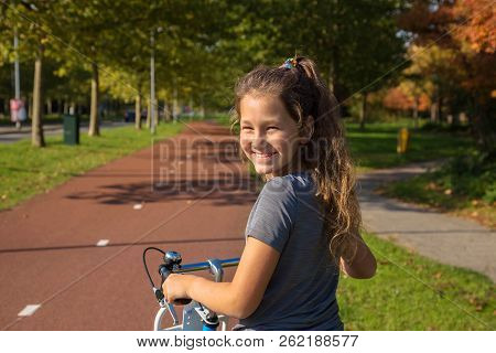 Child Rides A Bike On A Bike Path. Cyclist Child Or Teenager Girl Enjoys Good Weather And Cycling. E