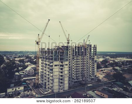 A View To The Multistorey Apartment Building Among Cottages. Initial Stage Of Multifamily House Buil