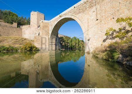 Arch Of Alcantara Bridge In Todedo Reflected In River Tagus