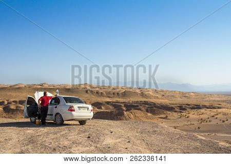 Aran Va Bidgol, Iran - August 12, 2015: Old Man With His White Car Observing The Dunes Of Maranjab D
