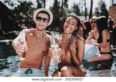Smiling Couple With Alcoholic Drinks At Poolside. Beautiful Black Woman And Young Man Holding Bottle