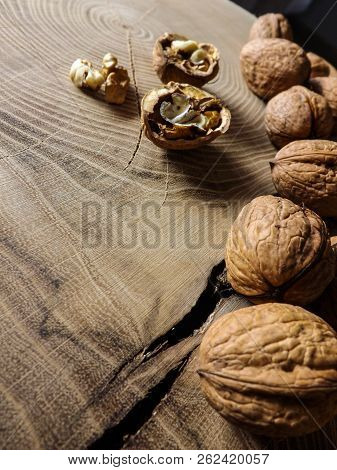 Some Walnuts On Wooden Table. Slice Of Wood