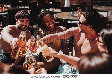 Young Friends With Alcoholic Drinks At Poolside. Group Of Young Smiling People Holding Bottles Of Be