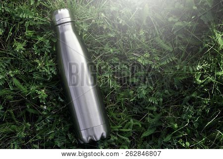 Stainless Thermos Water Bottle, Isolated On Grass Background.