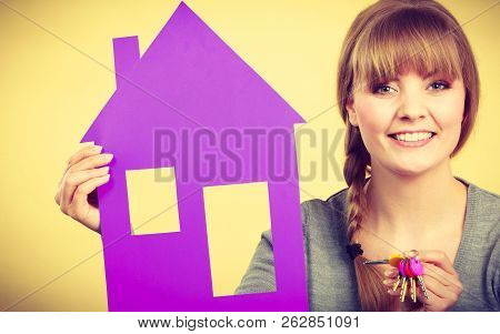 Ownership And Property Concept. Young Blonde Smiling Female Owner With Bunch Of Colorful Keys And Ho
