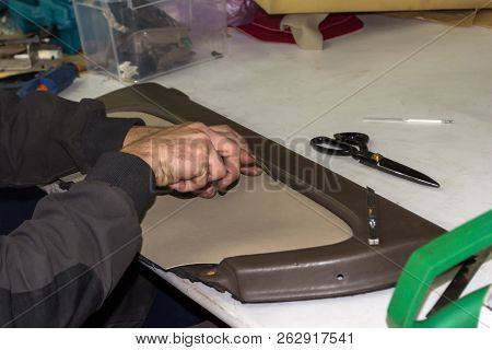 A Male Worker Does Manual Work On Skinning A Genuine Leather Of A Vehicle's Interior With A Beige-co