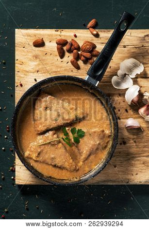 high angle view of a frying pan with some pieces of a homemade truita amb suc, a recipe of spinach omelet with a thick sauce made with nuts and garlic, typical of Catalonia, Spain, on a wooden table