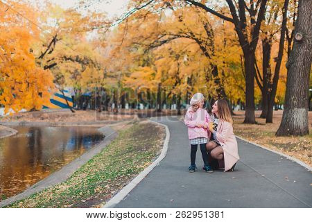 Stylish Mohter And Child Girl 5-6 Year Old Wearing Trendy Pink Coat In Autumn Park. The Girl Is Dres