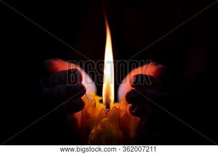 Close Up Hand Protecting Candle Light From The Wind In Darkness On Black Background