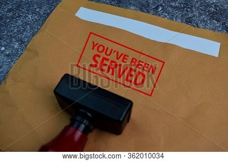 Red Handle Rubber Stamper And You've Been Served Text Isolated On The Table.