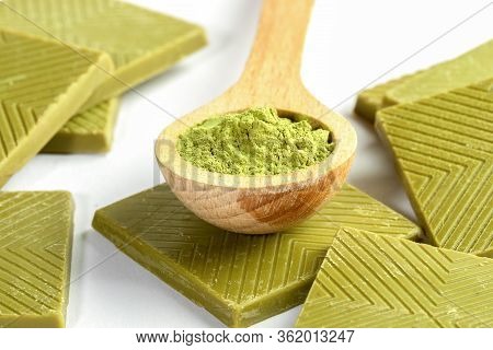 Close-up Wooden Spoon Of Japanese Matcha Tea Powder And Set Of Square Slices Of Green Chocolate With