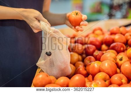 A Woman Chooses Tomatoes In A Supermarket Without Using A Plastic Bag. Reusable Bag For Buying Veget