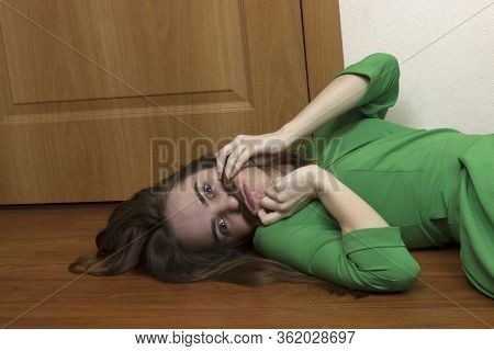 A Beautiful Long-haired Blonde Girl Is Fooling Around, Lying On The Floor Near The Door, Making A Mu