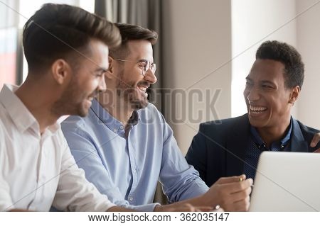 Diverse Colleagues Having Fun Telling Anecdotes Joking At Workplace