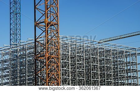 Construction Crane With A Metal Structure Frame Being Built Below.