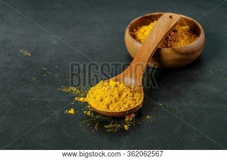 Turmeric Powder In Wooden Spoon And In Wooden Bowl Closeup On The Dark Background. Immunomodulator, 