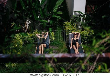Two Young Women Tan Under A Tropical Sun Behind A Fence