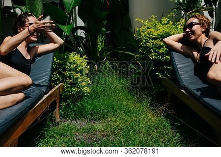 Lively Conversation Between Two Young Women On Deck Chairs