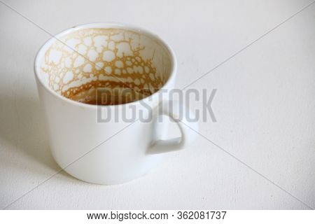 Dirty Empty Coffee Cup Closeup On White Table. Top View Empty And Dirty Cup Of Coffee On A White Bac