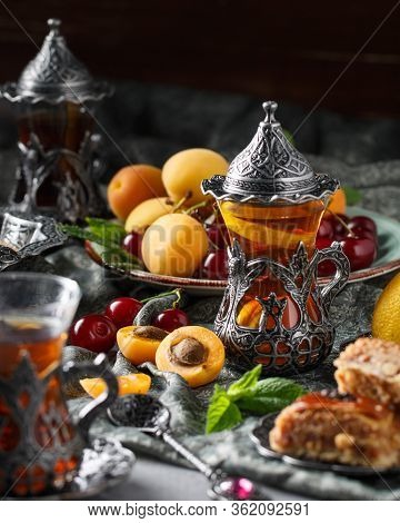 Tea Armud In Turkish Style With Lemon. Served On A Silk Tablecloth With Baklava And Fruit-cherries A
