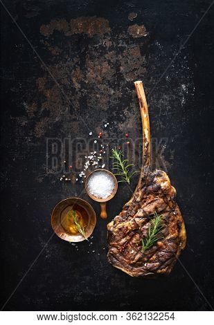 Grilled tomahawk beef steak with spices on dark rustic background