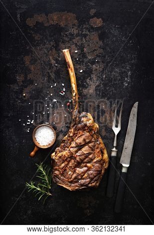 Grilled tomahawk beef steak with spices on dark rustic background