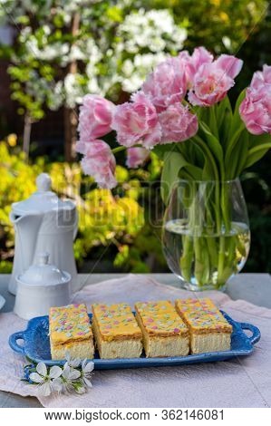 Four Tompouce Cakes With Whipped Cream And Yellow Icing Served In Sunny Spring Garden