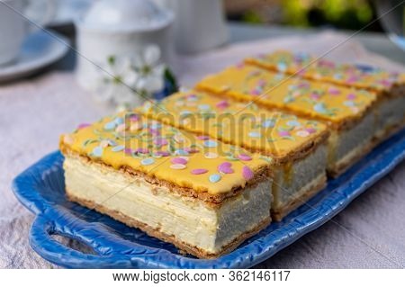 Four Tompouce Cakes With Whipped Cream And Yellow Icing Served In Sunny Spring Garden