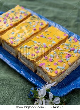 Four Tompouce Cakes With Whipped Cream And Yellow Icing Served In Sunny Spring Garden