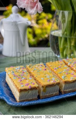 Four Tompouce Cakes With Whipped Cream And Yellow Icing Served In Sunny Spring Garden