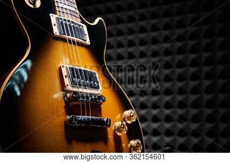 Sunburst Electric Guitar Standing Over Acoustic Foam Panel Background