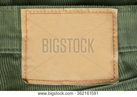 Blank Craft Paper Clothes Label On Green Tetile Background Closeup