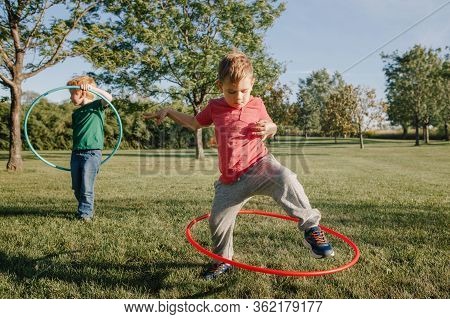 Two Funny Caucasian Preschool Boys Playing With Hoola Hoop In Park Outside. Kids Sport Activity. Lif