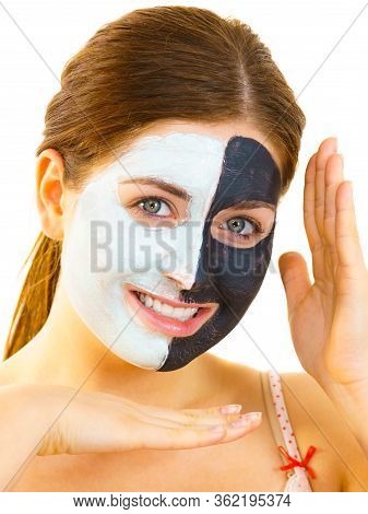 Woman With Clay Carbo Black Mask On Half Face And White Mud On Second Half. Girl Taking Care Of Oily